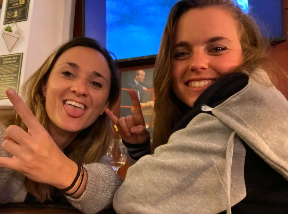 Becky and Giulia throwing metal horns in a pub